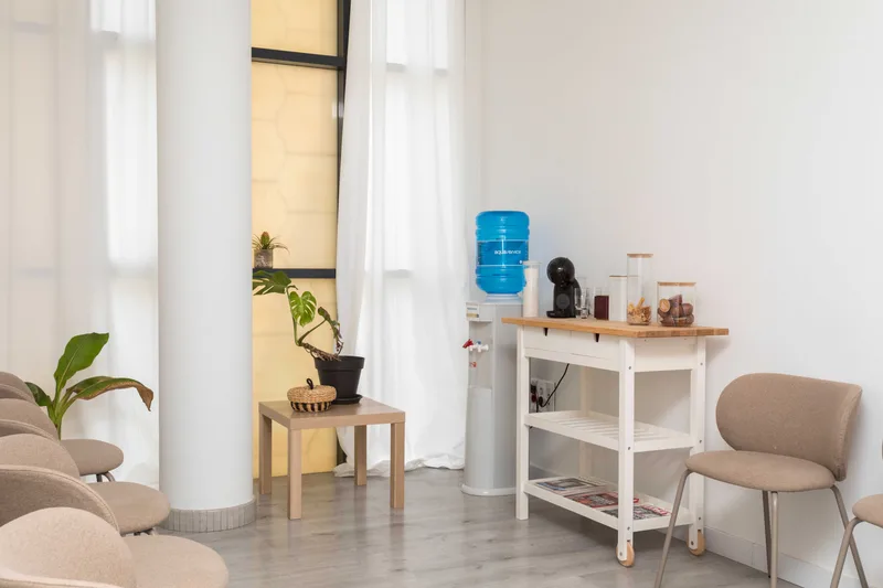 Rincón de la sala de espera, con agua y café a disposición de los pacientes