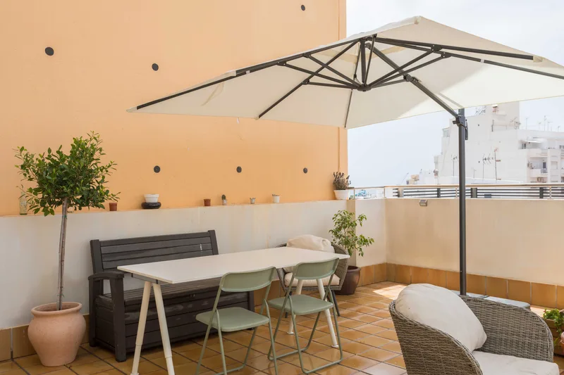 Terraza con mesa, sillas y un olivo